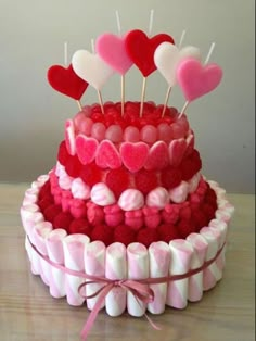 a red and white cake topped with lots of heart shaped lollipops on top of it