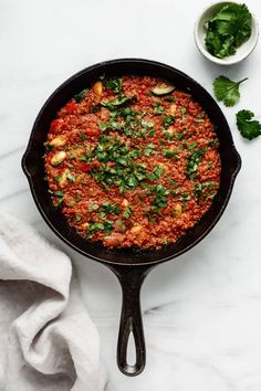 a skillet filled with food sitting on top of a white counter next to a napkin