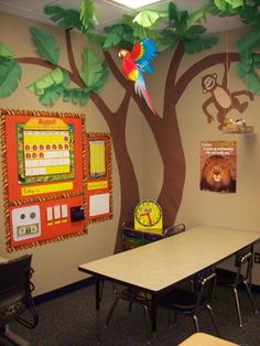 a classroom with a tree painted on the wall and an arcade machine next to it