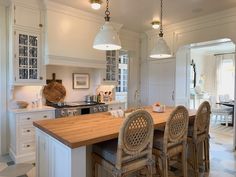 a kitchen with white cabinets and wooden counter tops next to an island in the middle