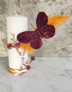 a white pillar with a purple butterfly on it next to a red and orange flower