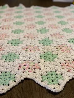 a crocheted table cloth on top of a wooden table