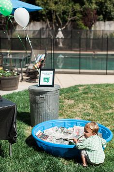 a little boy playing in a pool filled with money and balloons on top of it