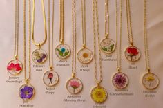 a bunch of necklaces that have different flowers on them and names in the middle