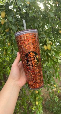 a hand holding up a starbucks cup with orange sprinkles on the outside