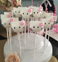 hello kitty lollipops with pink bows are on a white cake platter