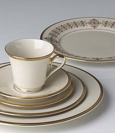 a set of gold and white dinnerware with matching saucers, plates and cups