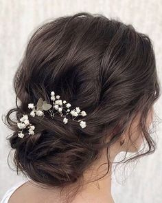 a woman wearing a hair comb with flowers on it's side, in front of a white wall