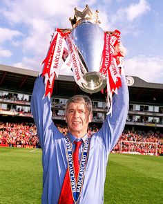 a man holding up a silver trophy on top of a field