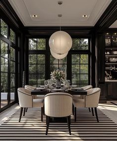 an elegant dining room with black and white striped carpet, large windows, chandelier and round table surrounded by beige chairs