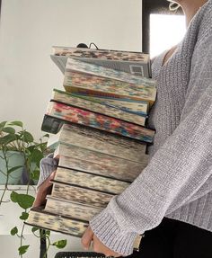 a woman holding a stack of magazines in her hands