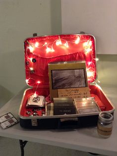 an open suitcase sitting on top of a table filled with books and other items next to a candle