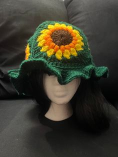 a crocheted sunflower hat sits on top of a mannequin head