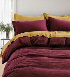 a bed covered in maroon and yellow sheets