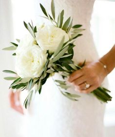 a bride holding a bouquet of white flowers