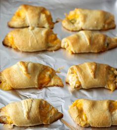 six cheesy pastries are lined up on a baking sheet