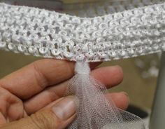 a hand holding a piece of white lace