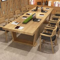 a large wooden table with laptops on it in a room filled with bookshelves