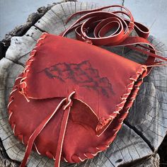 a red leather bag sitting on top of a tree stump next to a piece of wood