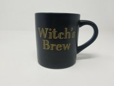 a black coffee mug with the words witch's brew on it and gold lettering