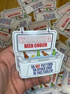 a hand holding up a sticker that says warning beer cooler do not put food in this cooler