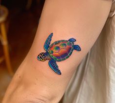 a colorful turtle tattoo on the left inner forearm and foot, with an ocean theme