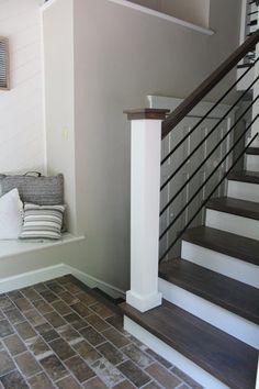 a set of stairs leading up to a living room with pillows on the floor and in front of it