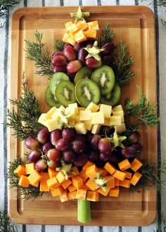 a christmas tree made out of fruits and cheese on a cutting board with pine branches