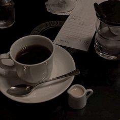 a cup of coffee sitting on top of a white saucer next to a spoon