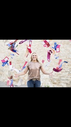 a woman standing in front of a stone wall with colorful streamers coming out of her hands