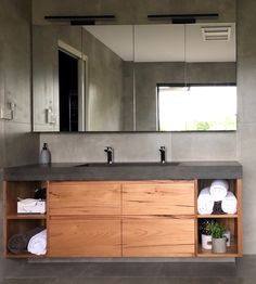 a bathroom with a large mirror above the sink and wooden cabinets below it, along with white towels