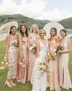 a group of women standing next to each other in front of an open field holding umbrellas