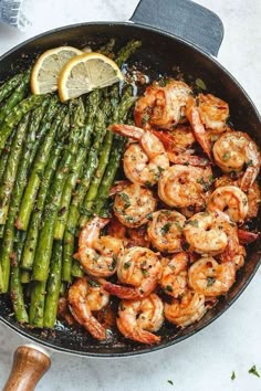 shrimp and asparagus in a skillet with lemon wedges on the side