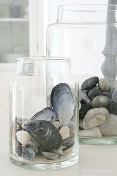 two glass jars filled with rocks and shells