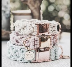 three crocheted bracelets with metal clasps on top of a table next to a potted plant