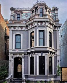 an old victorian style house in the middle of a city with lots of windows and balconies