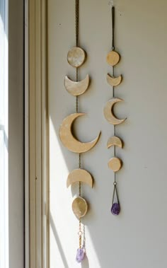 three wooden moon and crescent hangings on a wall next to a window sill