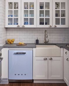 a kitchen with white cabinets and blue dishwasher on the counter top in front of an oven