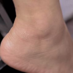 a small white star tattoo on the side of a person's foot and ankle