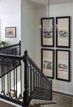 a staircase with pictures on the wall and chandelier hanging from it's handrail