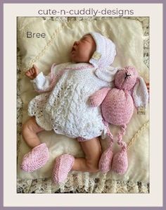 a baby laying on top of a bed next to a pink stuffed animal and some crocheted shoes