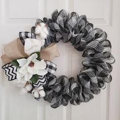 a black and white wreath with flowers hanging on the front door, decorated with burlap