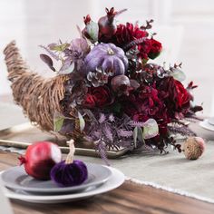 an arrangement of flowers on a table with plates and silverware, along with other items