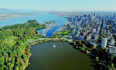 an aerial view of a large city with lots of trees and water in the foreground