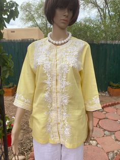 "Vintage blouse / light jacket circa 1960's.  Can be worn as a blouse by itself or as a light jacket over a T shirt. It is of a lovely pale yellow, and embroidered all over the front and on the sleeves with white designs.  Round collar, it closes down the front with 6 small buttons, frog style. It falls straight down and opens up on each side with a 7 1/2 \" slit. The sleeves are three quarter, and embroidered around the wrist. And for a bonus it is a good size by today's standards.  Measurement White Embroidered Shirt, White Cotton Blouse, Minimalist Shirts, White Knit Sweater, Yellow Shirt, Simple Blouse, Polka Dot Shirt, Santa Fe Nm, Yellow Shirts