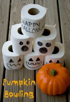 pumpkins and rolls of toilet paper with happy halloween written on them sitting on a wooden table