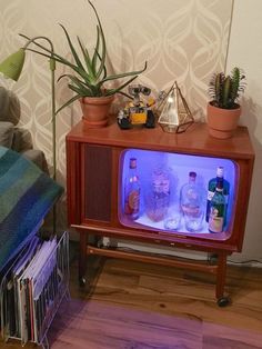 an old fashioned tv sitting on top of a wooden stand next to a potted plant