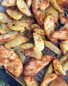 chicken and potatoes on a baking sheet with a wooden spoon