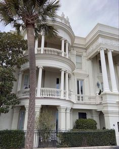 a large white building with two balconies and a palm tree in front of it