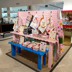 there is a pink bench with many items on it in front of a store display